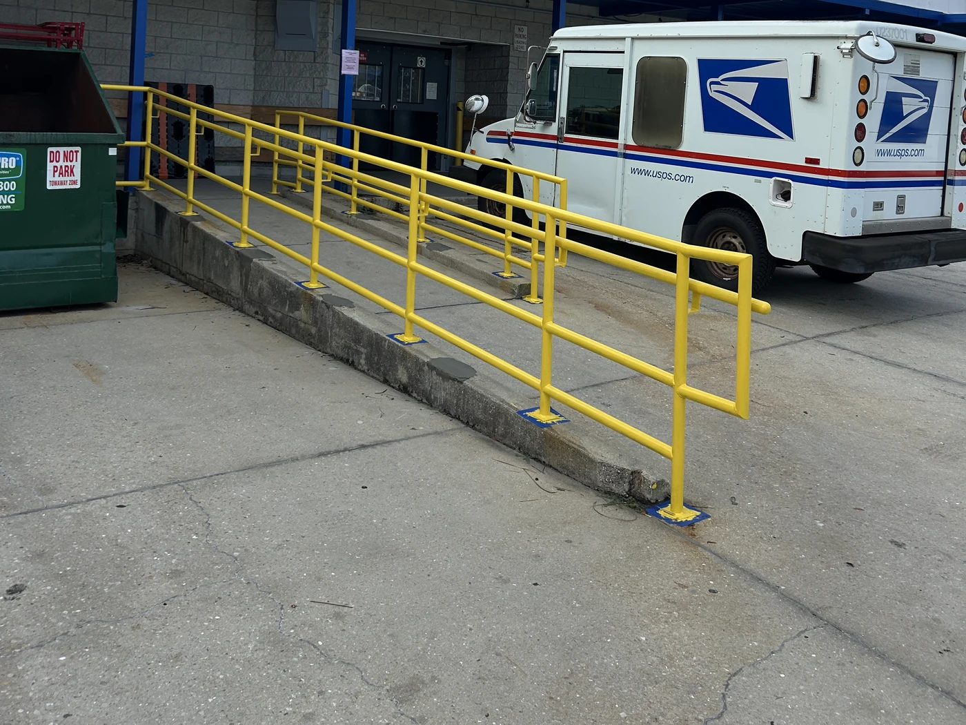 Finished yellow post office ramp handrails fabricated by On Time Welding